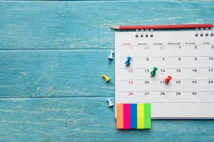 Calendar with pins and notes on a blue wooden table