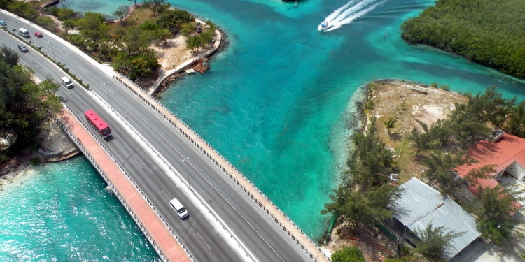 Car and bus crossing a river bridge