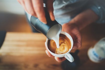 Milk pouring into fresh coffee