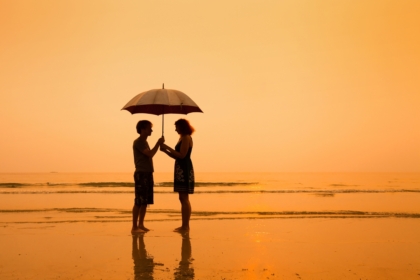 Couple standing on a beach with an umbrella