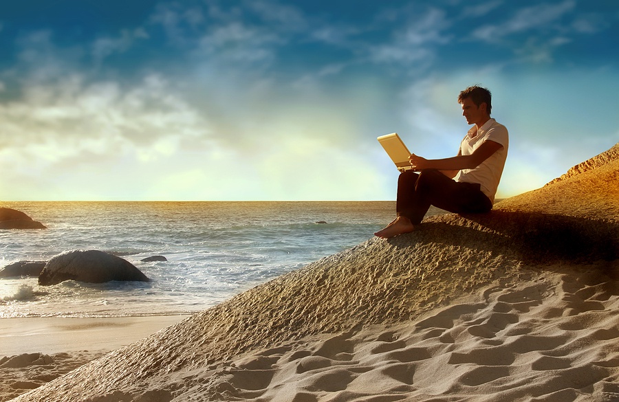 Man using laptop on a beach