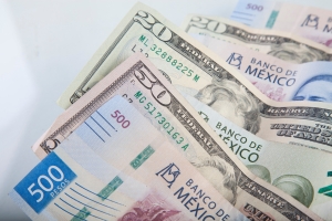 Mexican peso and US dollar banknotes interwoven together